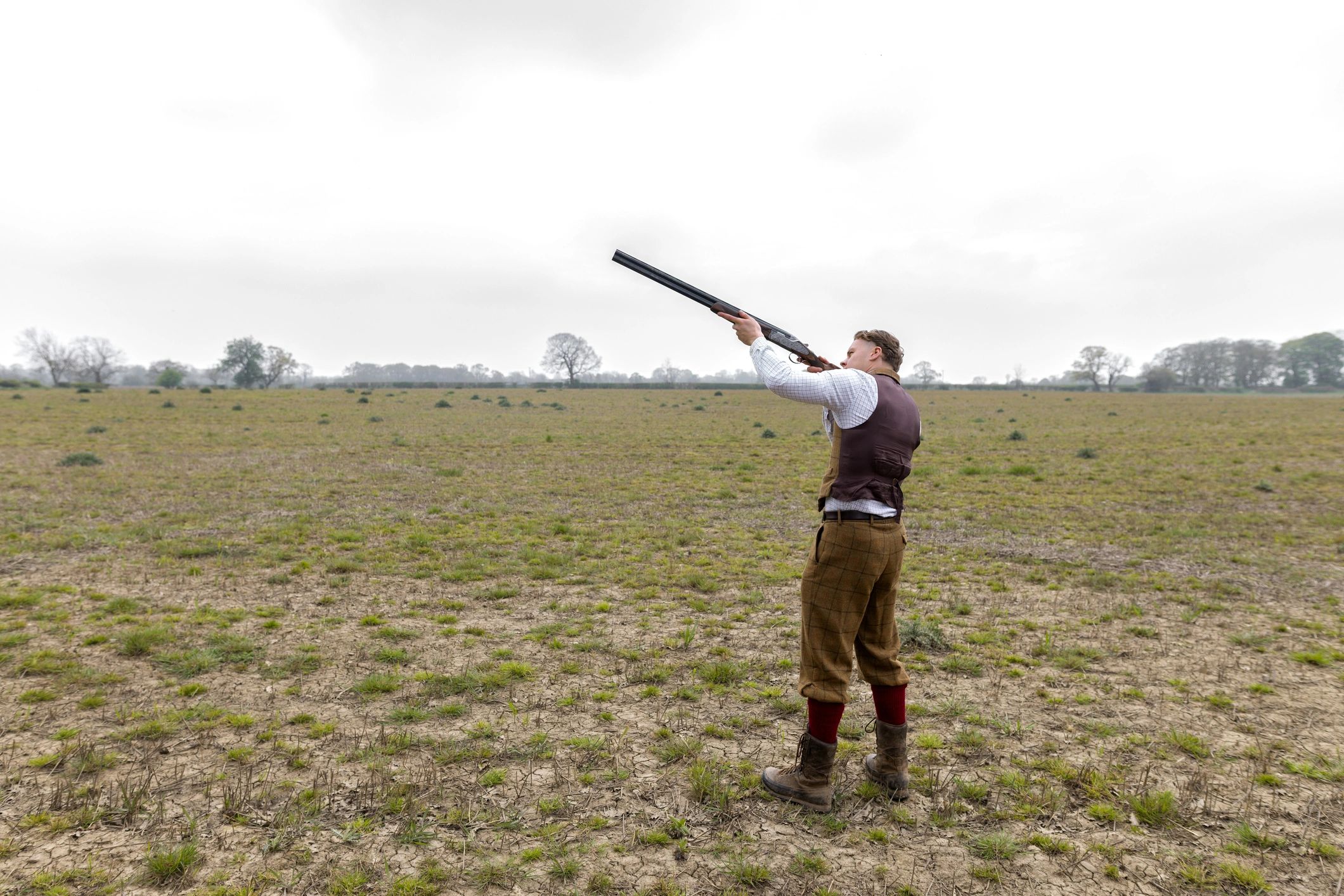 Hunter aiming in open country, representing optics and field readiness