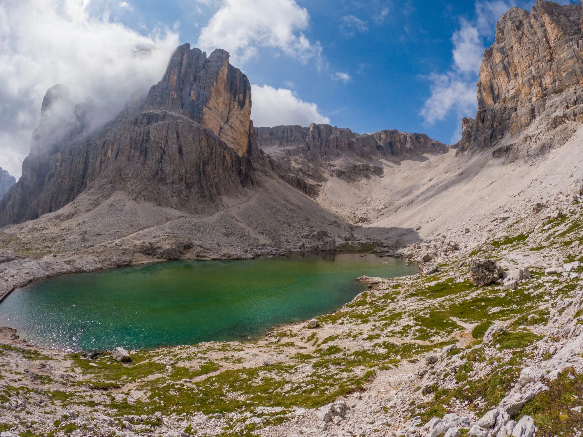 Emerald alpine lake surrounded by rocky peaks and lush greenery