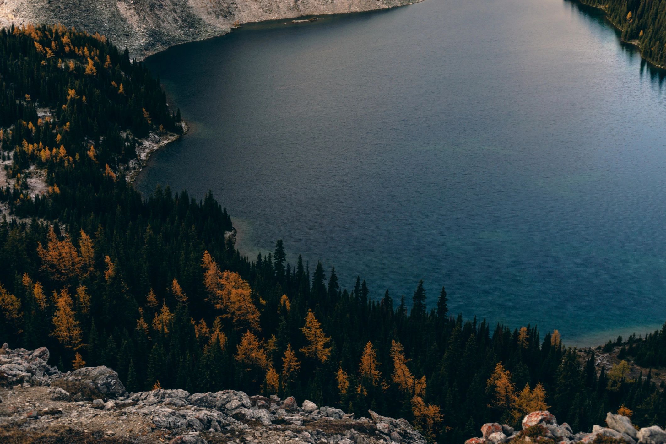 Aerial View of Alpine Mountain Lake Surrounded by Forest and Autumn Foliage in Rocky Landscape