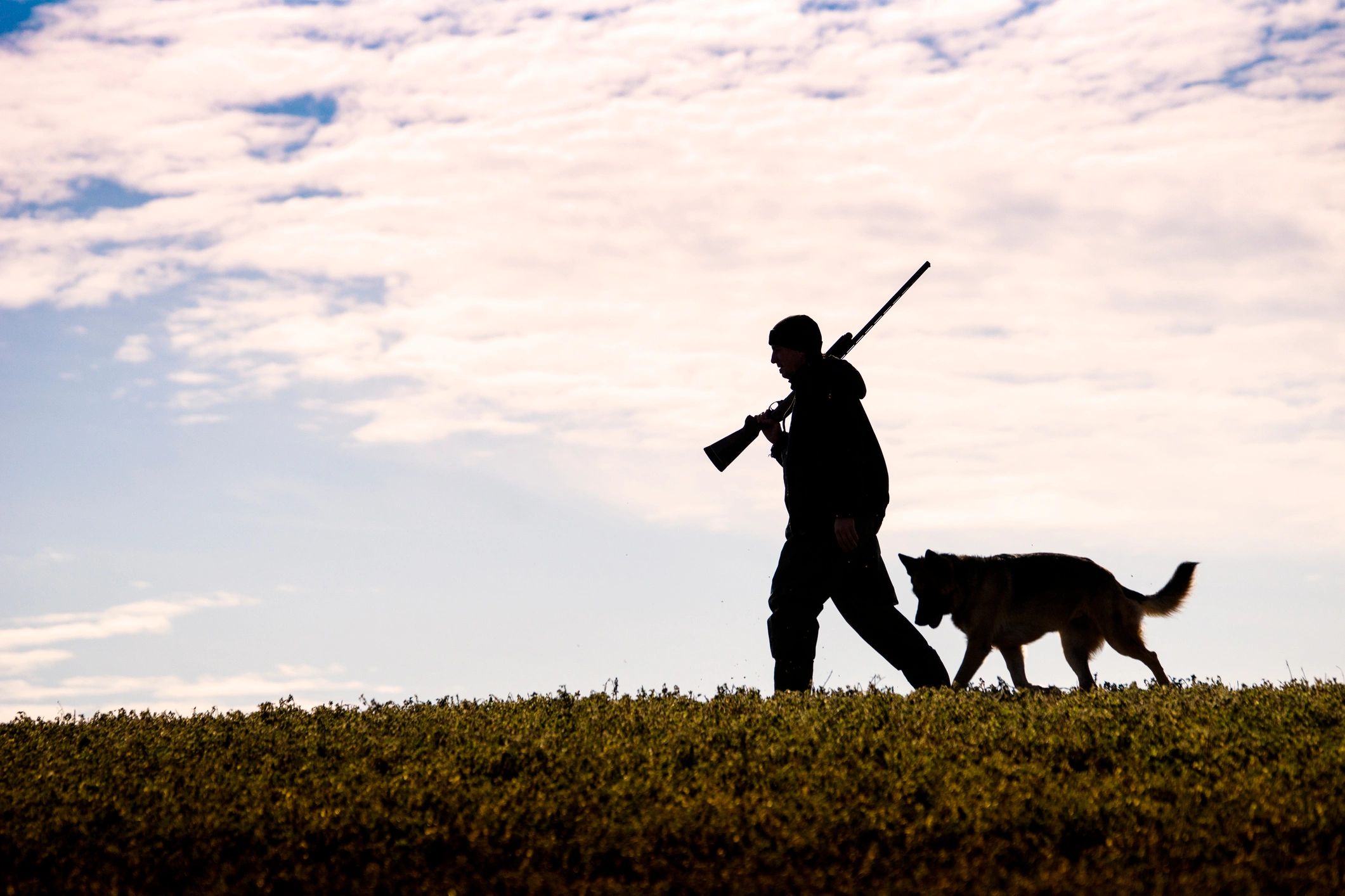 Hunter walking across open terrain with gear, representing pack selection